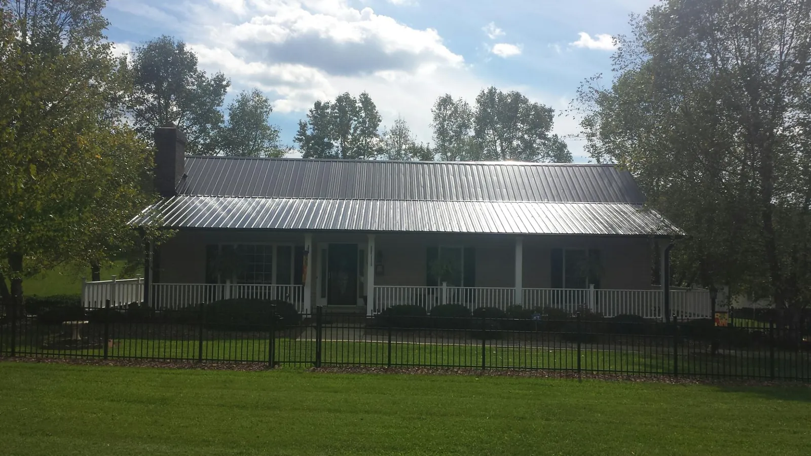 Gray metal roof on a brick ranch with a full width front porch — Gutter Guard Installation work by our crew in Edgewater